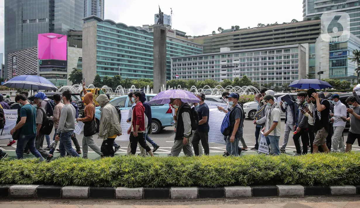 Ratusan imigran Afghanistan jalan kaki menuju Kedubes Kanada di Jakarta, Senin (13/12/2021). Dengan membawa spanduk dan poster, mereka menuntut UNHCR dan IOM segera memproses penempatan mereka ke negara tujuan seperti Kanada, Australia, Selandia Baru maupun AS. (Liputan6.com/Faizal Fanani)