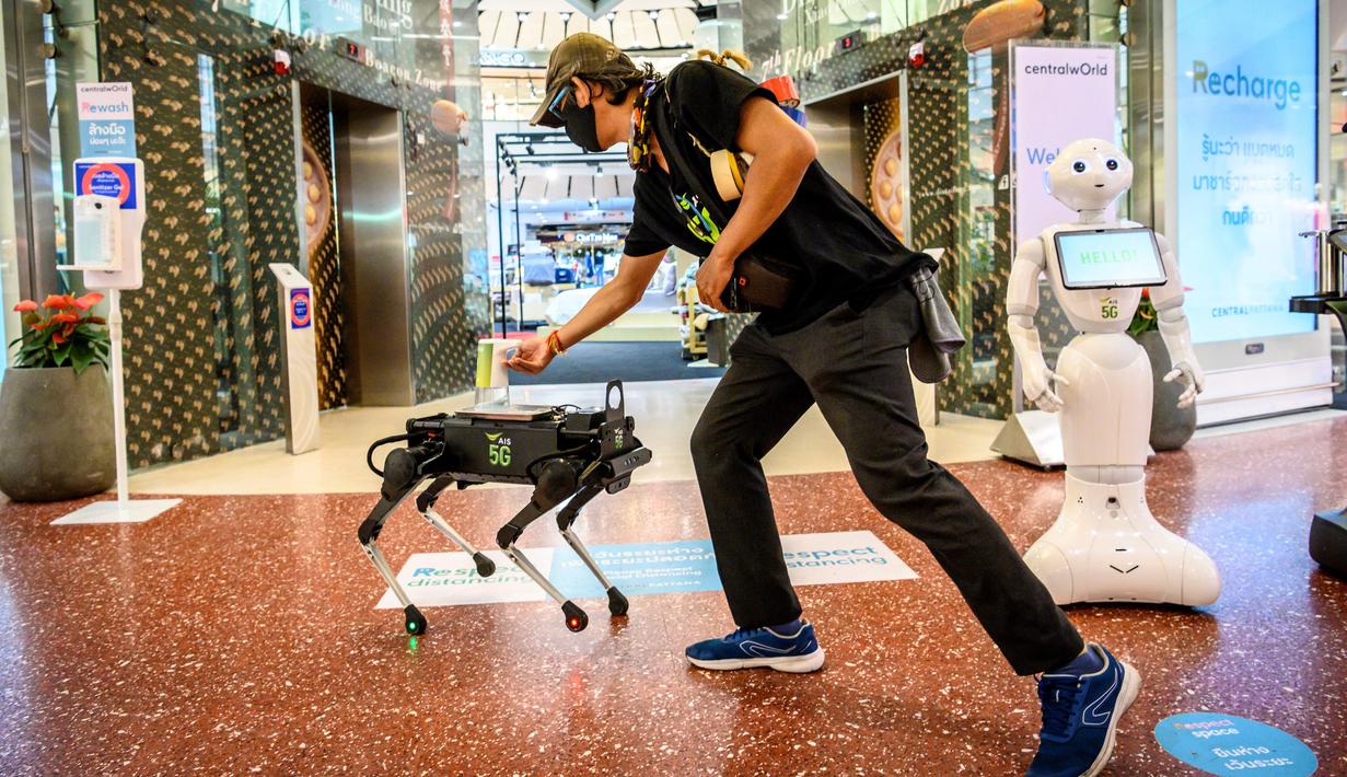 Robot 5G K9 memberikan hand sanitiser atau cairan pembersih tangan kepada pengunjung di pusat perbelanjaan di Bangkok, Kamis (4/6/2020). Thailand menggunakan teknologi di garis depan untuk menjaga ruang publik dari penyebaran pandemi corona Covid-19. (Mladen ANTONOV / AFP)