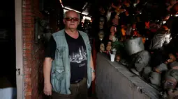 Seorang kolektor bernama Etanis Gonzalez berpose di samping koleksi boneka seram dan menakutkan yang dipajang di balkon rumahnya, di Caracas, Venezuela, 16 Juli 2016. (REUTERS/Carlos JASSO)
