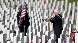 Pensiunan Angkatan Laut Amerika Serikat Yeoman Mark Stallins memainkan Taps untuk keluarga prajurit yang gugur di sebuah kuburan di Pemakaman Nasional Fort Logan, Sheridan, Colorado, Amerika Serikat, 30 Mei 2022. (AP Photo/David Zalubowski)
