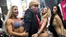 Seorang seniman berpenampilan seperti Donald Trump meraba-raba wanita seksi berbikini saat berada di depan Trump Tower di New York, (25/10). Aksi ini dilakukan oleh seniman Alison Jackson. (AFP Photo/Drew Angerer/Getty Images)