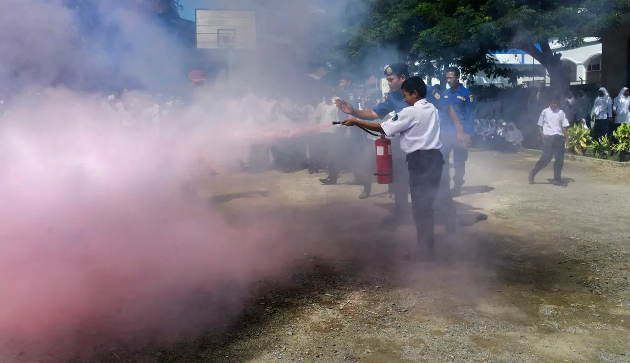 Seorang siswa berlatih memadamkan api menggunakan alat pemadam di Banda Aceh, Senin (11/11/2019). Para pelajar melihat, mempelajari, dan mendapatkan praktik langsung penanganan kebakaran yang disebabkan kompor gas juga cara pemadaman dengan racun api. (CHAIDEER MAHYUDDIN/AFP)