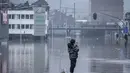 Seorang warga berdiri di atas balok kayu yang terendam banjir setelah Sungai Meuse jebol saat banjir besar di Liege, Belgia, Kamis (15/7/2021). Curah hujan yang tinggi menyebabkan banjir di beberapa provinsi di Belgia dengan hujan diperkirakan berlangsung hingga Jumat. (AP Photo/Valentin Bianchi)