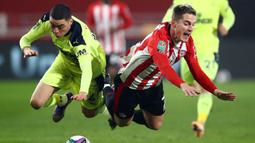Gelandang Newcastle United, Miguel Almiron (kiri) dan striker Brentford, Sergi Canos, terjatuh usai perebutan bola dalam laga perempatfinal Piala Liga Inggris Carabao Cup di Brentford Community Stadium, Selasa (22/12/2020). Newcastle United kalah 0-1 dari Brentford. (AFP/Hannah McKay/Pool)