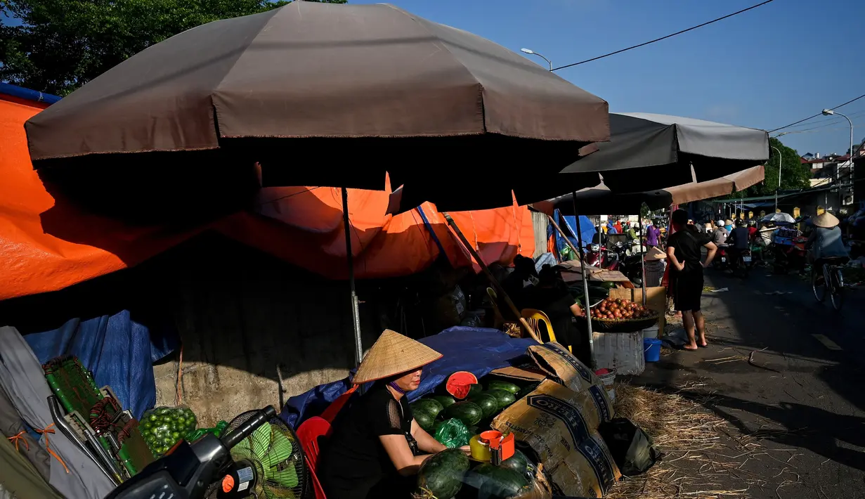 Penjual yang menjual semangka menunggu pelanggan di pasar grosir di Hanoi (26/8/2020). (AFP Photo/Manan Vatsyayana)