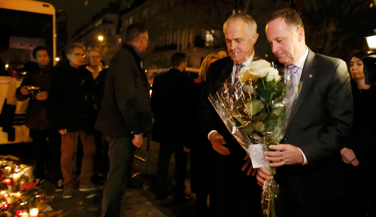 PM Australia Malcolm Turnbull  (kiri) dan PM Selandia Baru John Key menaruh bunga tanda bela sungkawa di salah satu lokasi serangan berdarah Paris di gedung konser Bataclan, Prancis, Minggu (30/11). (REUTERS/Gonzalo Fuentes)