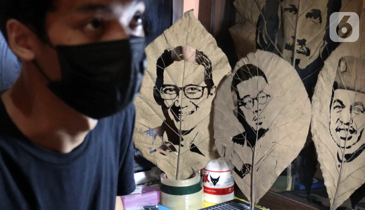Hadi Muhammad (24) saat menyelesaikan pembuatan lukisan siluet melalui media daun jati kering di kawasan Benda Baru, Pamulang 2, Tangerang Selatan, Rabu (13/10/2021). Lukisan tersebut memanfaatkan daun jati berguguran yang dipungut dari seputar Depok dan Tangsel. (merdeka.com/Arie Basuki)