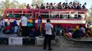Pekerja migran dan anggota keluarga mereka berkumpul di luar terminal bus Anand Vihar untuk pulang ke kampung halamannya, di New Delhi, Sabtu (28/3/2020). Ribuan orang meninggalkan New Delhi setelah pemerintah India memberlakukan lockdown untuk mencegah penyebaran COVID-19. (Bhuvan BAGGA/AFP)