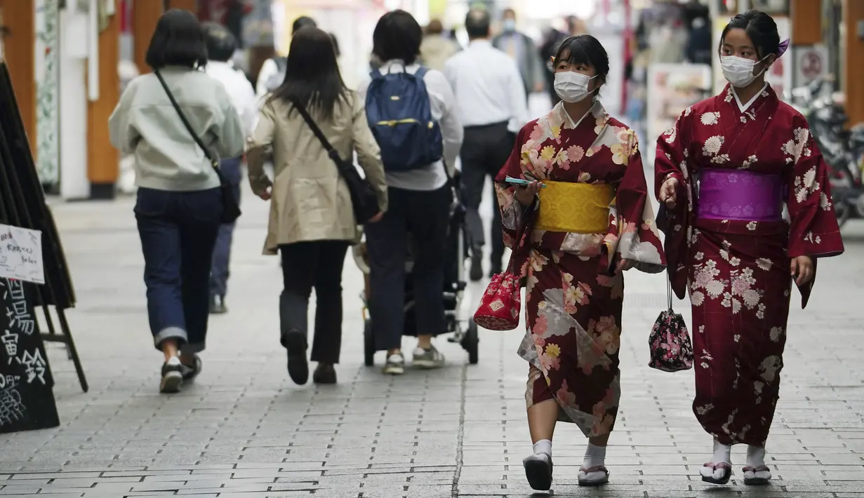 Orang-orang yang mengenakan masker pelindung untuk membantu mengekang penyebaran virus corona berjalan melalui arena perbelanjaan di distrik Asakusa di Tokyo, Rabu (31/3/2021).  Ibukota Jepang mengonfirmasi lebih dari 410 kasus virus corona baru pada hari Rabu. (AP Photo/Eugene Hoshiko)