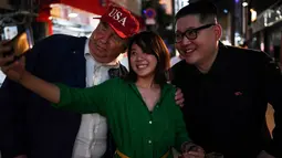 Seorang wanita berswafoto dengan peniru pemimpin Korea Utara Kim Jong-un dan peniru Presiden AS, Donald Trump selama gelaran KTT G20 di Osaka, Jepang, Jumat (28/6/2019). Sejumlah pemimpin dunia berkumpul dalam KTT G20 yang berlangsung dua hari di Osaka. (Charly TRIBALLEAU/AFP)