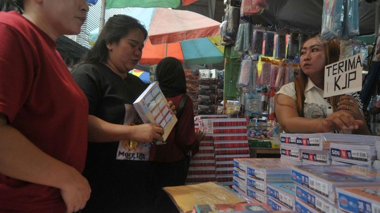 Pedagang menawarkan perlengkapan alat tulis sekolah kepada calon pembeli di Pasar Asemka, Jakarta (4/7/2024). Memasuki tahun ajaran baru sekolah, buku tulis mulai laris manis diserbu orang tua murid. Foto: merdeka.com / Imam Buhori