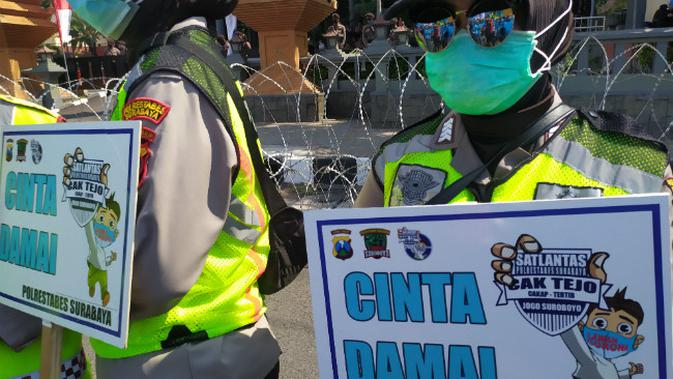 Sejumlah Polwan membawa spanduk bertuliskan Satlantas Polrestabes Surabaya cinta damai saat mengamankan demo UU Cipta Kerja, Kamis (22/10/2020). (Foto: Liputan6.com/Dian Kurniawan)