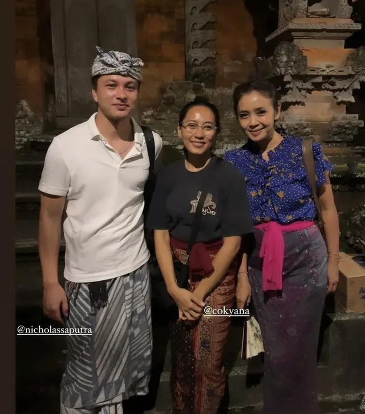 Nicholas Saputra tampil dalam polo shirt putih dan kain abu-abu bercorak.