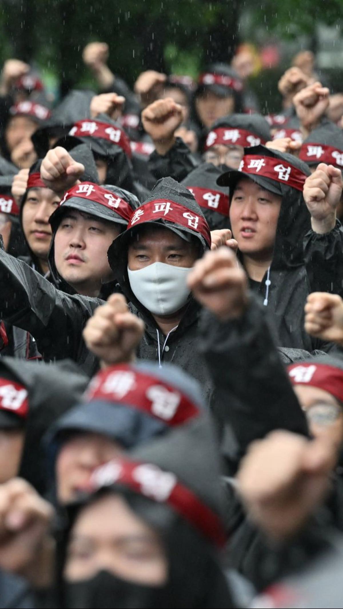 Dalam aksinya, ribuan buruh dengan mantel hitam dan ikat kepala merah berkumpul dan berbaris rapi di depan pabrik.&nbsp;Foto: Jung Yeon-je/AFP