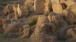Seorang wanita saat mengunjungi situs arkeologi Babilonia, Irak, Minggu (21/3/2021). Kawasan Babilonia seluas 10 kilometer persegi itu, baru 18 persen yang digali. (AP Photo/Hadi Mizban)