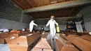 Pekerja menyemprotkan disinfektan di atas peti mati yang diletakkan di lantai kamar mayat di pemakaman Sarajevo Bare, Bosnia, Jumat (19/3/2021). Rumah sakit dan kamar mayat di Sarajevo kewalahan mengatasi meningkatnya infeksi dan lonjakan kematian yang disebabkan oleh virus corona. (AP Photo)
