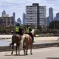 Polisi berpatroli dengan menunggang kuda di sepanjang St Kilda Esplanade di Melbourne (26/10/2020). Australia telah menghabiskan berbulan-bulan di bawah pembatasan yang berat setelah menjadi episentrum gelombang kedua negara itu. (AFP Photo/William West)