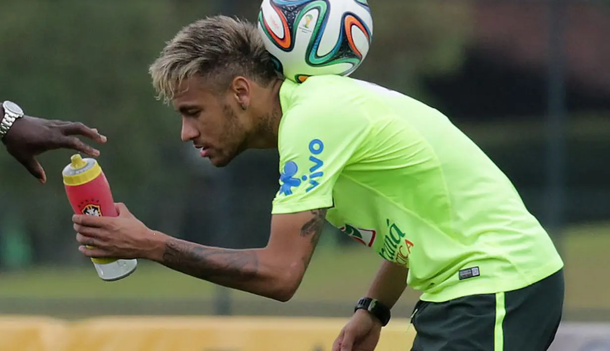Neymar menahan bola dipunggungnya saat meminta minum pada staf pelatih saat latihan menjelang kontra Meksiko, Brasil, Senin (16/6/2014) (AFP Photo/ARI VERSIANI)