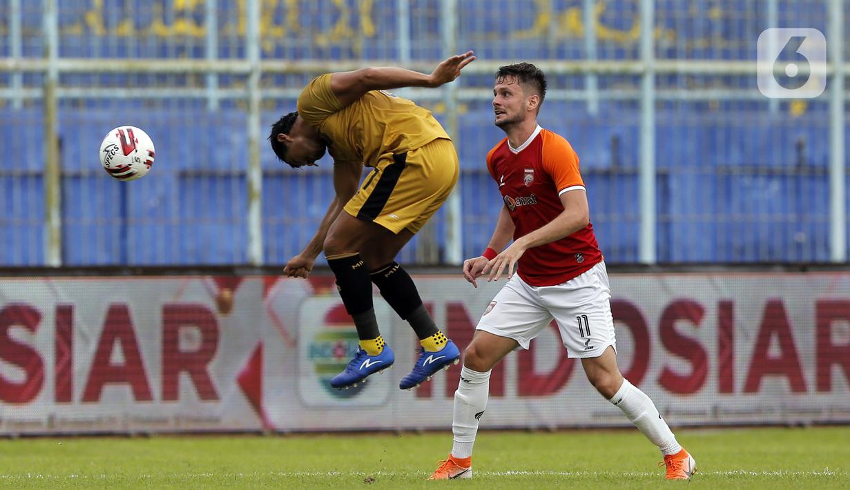 Pemain Bhayangkara Solo FC Jajang Mulyana menghalau bola dari pemain Borneo FC Samarinda Amer Bekic (kanan) dalam pertandingan babak penyisihan Piala Menpora 2021 di Stadion Kanjuruhan, Malang, Jawa Timur, Senin (22/3/2021). (Bola.com/Arief Bagus)