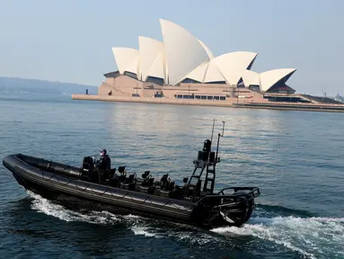 Sebuah kapal polisi berpatroli melewati Sydney Opera House (21/8/2021). Kota itu memperpanjang penguncian selama dua bulan dan memberlakukan jam malam sebagian untuk menahan wabah virus corona yang menyebar cepat. (AFP/David Gray)