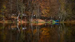 Orang-orang menikmati hari musim gugur yang cerah di Taman Nasional Yedigoller di distrik Bolu, Turki pada 9 November 2021. Taman Nasional Yedigoller mengundang banyak pecinta alam untuk berkemah, ataupun sekedar menikmati ketenangan. (Ozan KOSE / AFP)