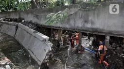 Petugas PPSU melintasi tembok jebol akibat derasnya arus banjir rob di Kompleks Perumahan Pantai Mutiara, Pluit, Jakarta, Minggu (7/6/2020). (merdeka.com/Iqbal S. Nugroho)