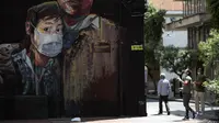 Sebuah mural menunjukkan seorang pemuda mengenakan masker selama pemerintahan setempat memberlakukan lockdown untuk mencegah penyebaran virus corona COVID-19 di Bogota, Kolombia, Senin (13/4/2020). (AP Photo/Fernando Vergara)
