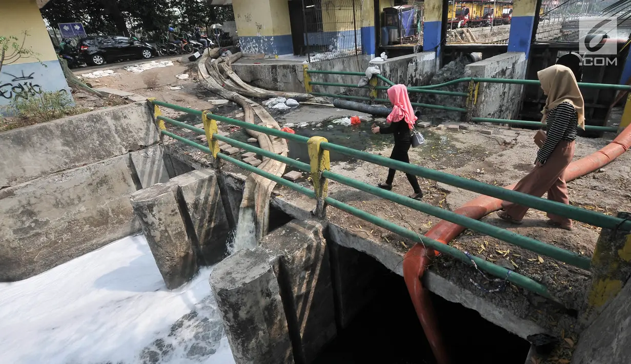 Warga melintas saat penyedotan Kali Item, Jakarta, Kamis (2/8). Penyedotan dilakukan yang jaraknya sekitar 2,6 kilometer dari Wisma Atlet ini bertujuan mengurangi debit air dan bau. (Merdeka.com/Iqbal S. Nugroho)
