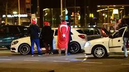 Warga Turki berkumpul membawa bendera negara Turki saat menggelar protes di Rotterdam, Belanda (11/3). Belanda melarang Menteri Luar Negeri Turki, Mevlut Cavusoglu untuk mendarat di Rotterdam, Belanda. (AFP/Emmanuel Dunand)