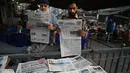 Orang-orang membaca koran pagi dengan berita utama pemilu di halaman depan di sebuah kios pinggir jalan sehari setelah pemilihan umum nasional Pakistan di Lahore pada tanggal 9 Februari 2024. (Aamir Qureshi/AFP)