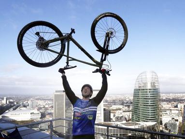 Pembalap sepeda asal Prancis, Aurelien Fontenoy, melakukan selebrasi usai berhasil mendaki 768 anak tangga dari 33 lantai gedung Trinity Tower di distrik La Defense, Paris, (17/1/2021). (AP/Christophe Ena)