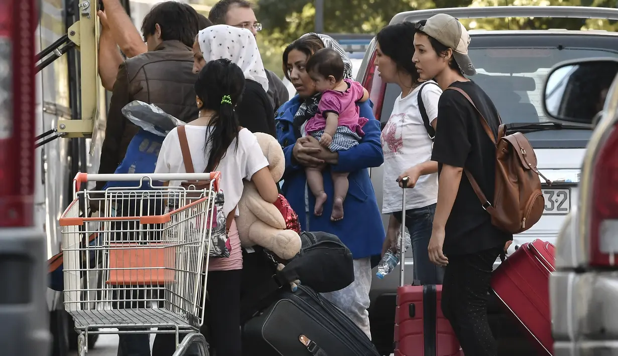 Para migran bersiap naik bus selama operasi polisi di pusat Athena, Yunani (19/9/2019). Polisi di Athena pada 19 September 2019 memindahkan lebih dari 200 migran, termasuk lusinan anak-anak, dari dua tempat di pusat kota sebagai bagian dari pembersihan. (AFP Photo/Louisa Gouliamaki)