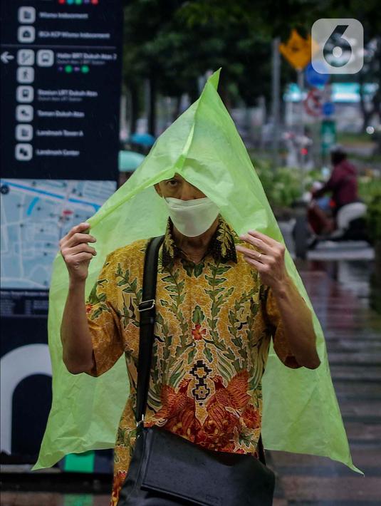 Warga menutupi kepala dari guyuran hujan saat melintasi kawasan Sudirman, Jakarta, Kamis (4/1/2024). (Liputan6.com/Angga Yuniar)