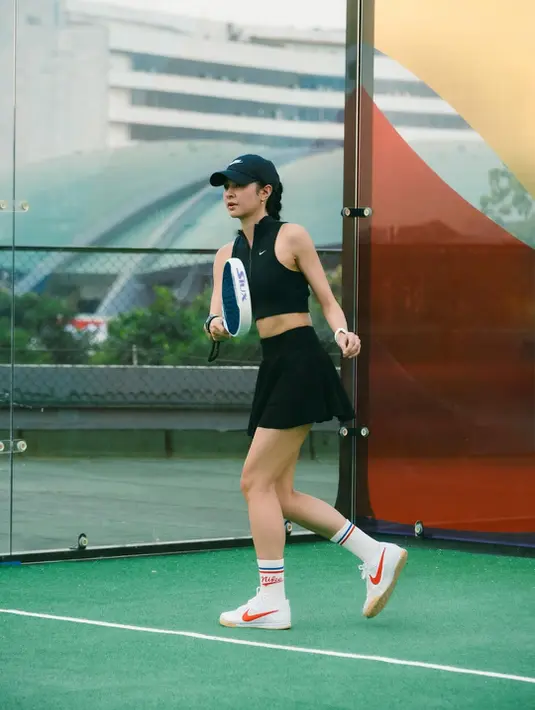 Dalam unggahan terbarunya, Mikha tampil sporty dalam balutan busana atletik serba hitam. Ia mengenakan crop top sleeveless dari Nike yang menampilkan kesan sleek dan dinamis, dipadukan dengan rok mini lipit yang memberi sentuhan feminin sekaligus fungsional untuk pergerakan di lapangan. [@miktambayong].