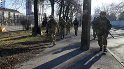 Tentara Ukraina berpatroli di daerah tidak jauh dari truk militer yang terbakar di sebuah jalan di Kyiv, Ukraina, Sabtu (26/2/2022). Pasukan Rusia menyerbu ke arah ibukota Ukraina Sabtu, dan pertempuran jalanan pecah saat pejabat kota mendesak penduduk untuk berlindung. (AP Photo/Efrem Lukatsky)
