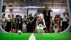 Pengunjung menyaksikan pertandingan sepak bola yang dimainkan oleh robot dari perusahaan teknologi Softbank pada Konferensi Robot Dunia di Beijing, China, Rabu (15/8). (AP Photo/Mark Schiefelbein)