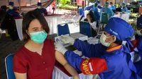 Seorang wanita menerima vaksin virus corona COVID-19 AstraZeneca di Denpasar, Bali, Sabtu (26/6/2021). Ratusan warga terlihat antusias mengikuti vaksinasi massal tersebut. (SONY TUMBELAKA/AFP)