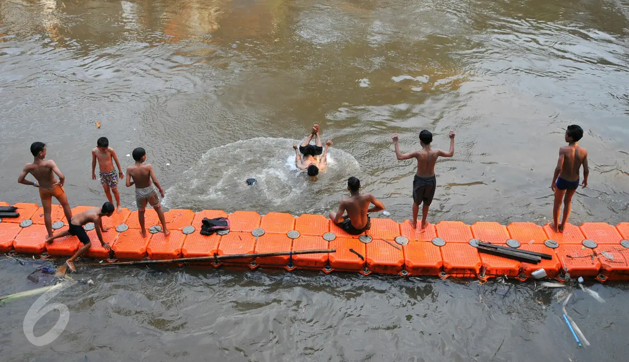 Anak-anak bermain di aliran Sungai Ciliwung, Jakarta, Rabu (18/5/2016). Meski belum terlalu bersih, seorang anak terlihat melompat untuk berenang di sungai tersebut. (Liputan6.com/Yoppy Renato)