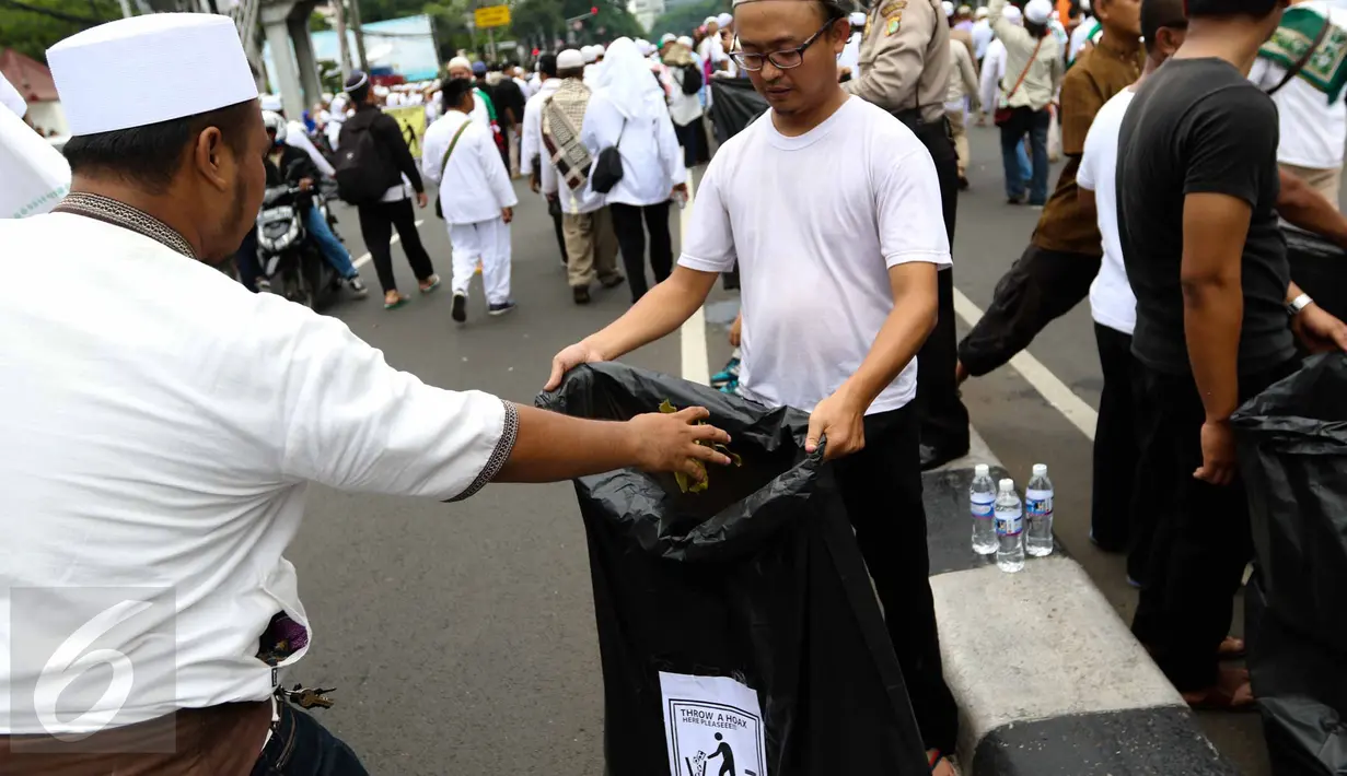 Massa membuang sampah ke kantong plastik yang disediakan oleh relawan di tengah aksi damai 4 November di Jakarta, Jumat (4/11). Mereka mengumpulkan sampah berupa bekas botol minuman dan bungkus nasi yang dibuang anggota ormas (Liputan6.com/Faizal Fanani)