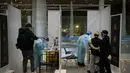 Pekerja mengenakan pakaian pelindung berdiri di bilik memeriksa pelancong yang tiba untuk menjalani tes COVID-19 di area kedatangan internasional di Bandara Internasional Ibukota Beijing di Beijing (9/1/2023). Pelancong internasional pertama tiba di China tanpa karantina wajib yang telah diberlakukan pada awal penerbangan. Pandemi tiga tahun lalu setelah pembatasan dicabut mulai hari Minggu. (AP/Mark Schiefelbein)