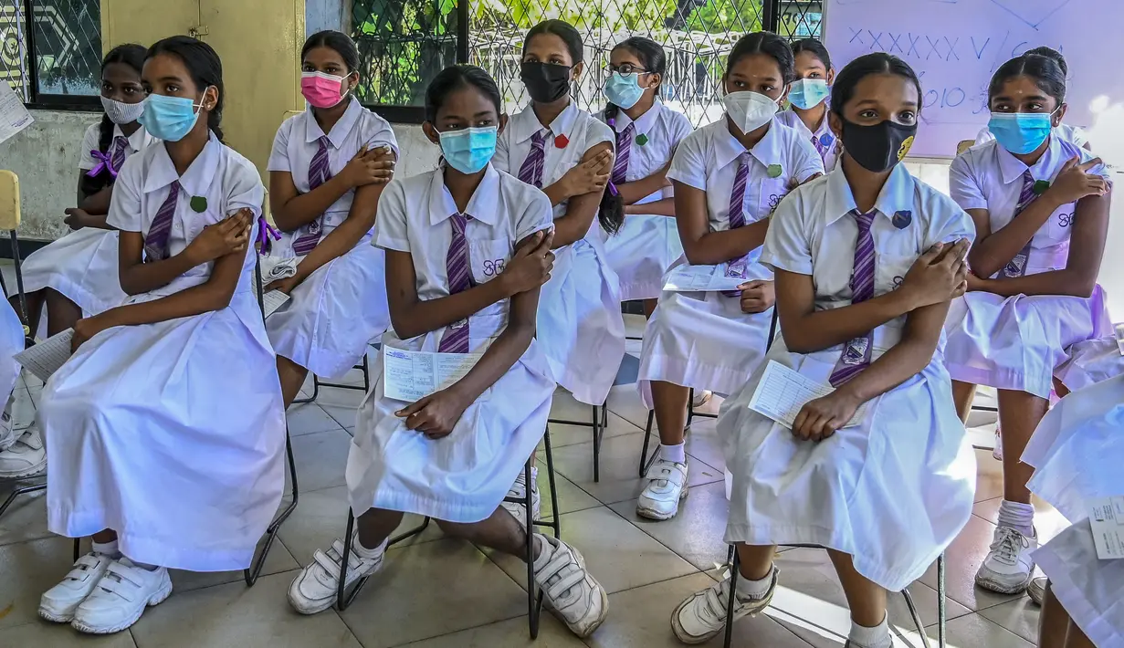 Para siswi menunggu di area observasi yang telah ditentukan setelah disuntik vaksin Pfizer-BioNTech dengan dosis vaksin Covid-19 untuk kelompok usia 12-15 tahun di sebuah lembaga pendidikan di Kolombo, Sri Lanka (7/1/2022). (AFP/Ishara S. Kodikara)