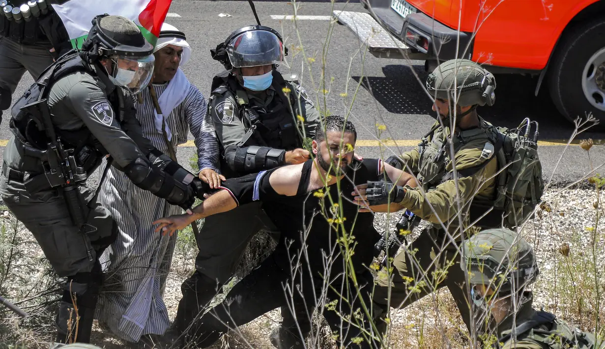 Tentara Israel mengamankan seorang pengunjuk rasa Palestina yang memprotes pembukaan lahan untuk permukiman Israel di dekat Desa Shoufah, wilayah Tepi Barat (20/8/2020). (AFP/JAAFAR ASHTIYEH)