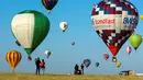 Pengunjung menyaksikan balon udara terbang di pangkalan udara Chambley-Bussieres, Hagéville, Prancis, Senin (29/7/2019). Festival balon udara tersebut dimanfaatkan para pilot balon udara untuk berkumpul. (Jean-Christophe VERHAEGEN/AFP)
