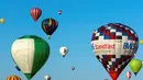 Pengunjung menyaksikan balon udara terbang di pangkalan udara Chambley-Bussieres, Hagéville, Prancis, Senin (29/7/2019). Festival balon udara tersebut dimanfaatkan para pilot balon udara untuk berkumpul. (Jean-Christophe VERHAEGEN/AFP)