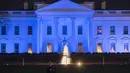 Seorang penjaga berdiri di depan Gedung putih yang dihiasi cahaya warna biru untuk menandai Hari Kesadaran Autisme Sedunia, di Washington, DC, Minggu (2/4). Tanggal 2 April diperingati sebagai Hari Kesadaran Autisme Sedunia. (SAUL LOEB/AFP)