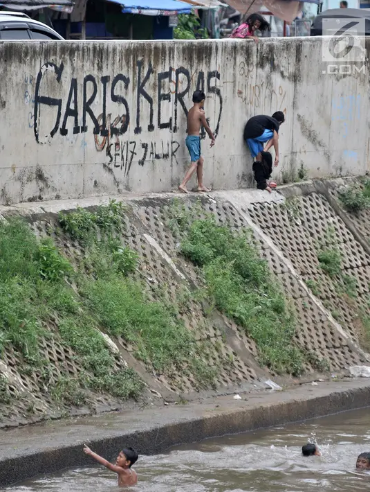 Anak-anak berenang di Kali Ciliwung, Kampung Pulo, Jakarta, Minggu (27/1). Keterbatasan ekonomi menjadikan Kali Ciliwung sebagai tempat pilihan bagi anak-anak setempat untuk menghabiskan waktu bermain saat libur sekolah. (Merdeka.com/Iqbal Nugroho)