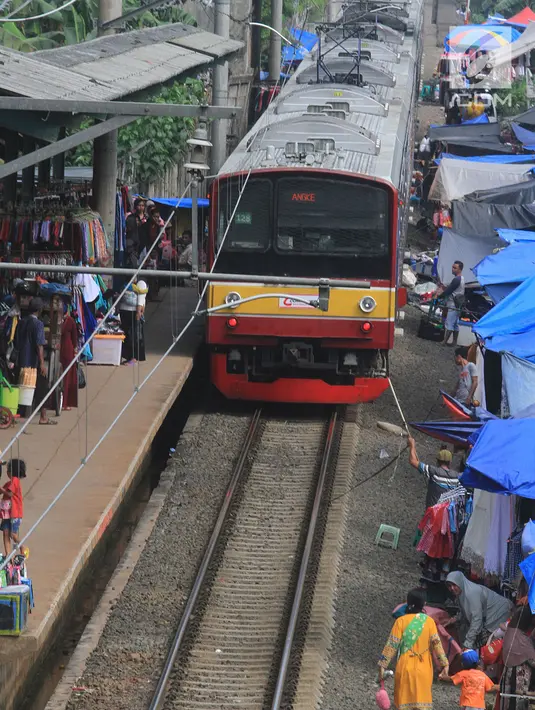 Kereta commuter line melintas di rel KRL Nambo yang dipadati aktivitas jual beli pasar dadakan, Citeureup, Bogor (20/4). Aktivitas jual beli di sisi rel ini juga berpotensi mengakibatkan kecelakaan. (Merdeka.com/Arie Basuki)