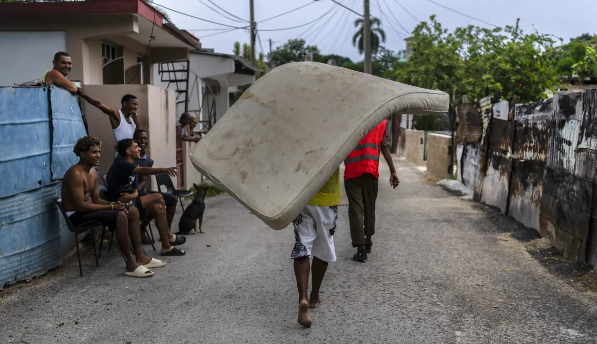 Warga lingkungan El Fanguito membawa kasur ke tempat yang aman untuk persiapan kedatangan Badai Ian, di Havana, Kuba, Senin, 26 September 2022. Badai Ian semakin kuat saat mendekati ujung barat Kuba pada trek untuk memukul pantai barat Florida sebagai badai besar pada awal Rabu. (AP Photo/Ramon Espinosa)