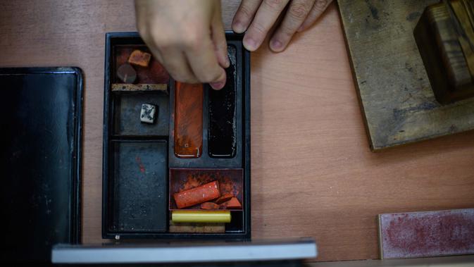 Pembuat stempel tinta tradisional Takahiro Makino, 44, menyiapkan tongkat tinta sebagai bagian dari langkah pembuatan hanko di studio di Tokyo pada 9 Oktober 2020. PM Yoshihide Suga tengah menggencarkan upaya digitalisasi dan menghapus Hanko atau stempel tinta tradisional Jepang. (Philip FONG/AFP)
