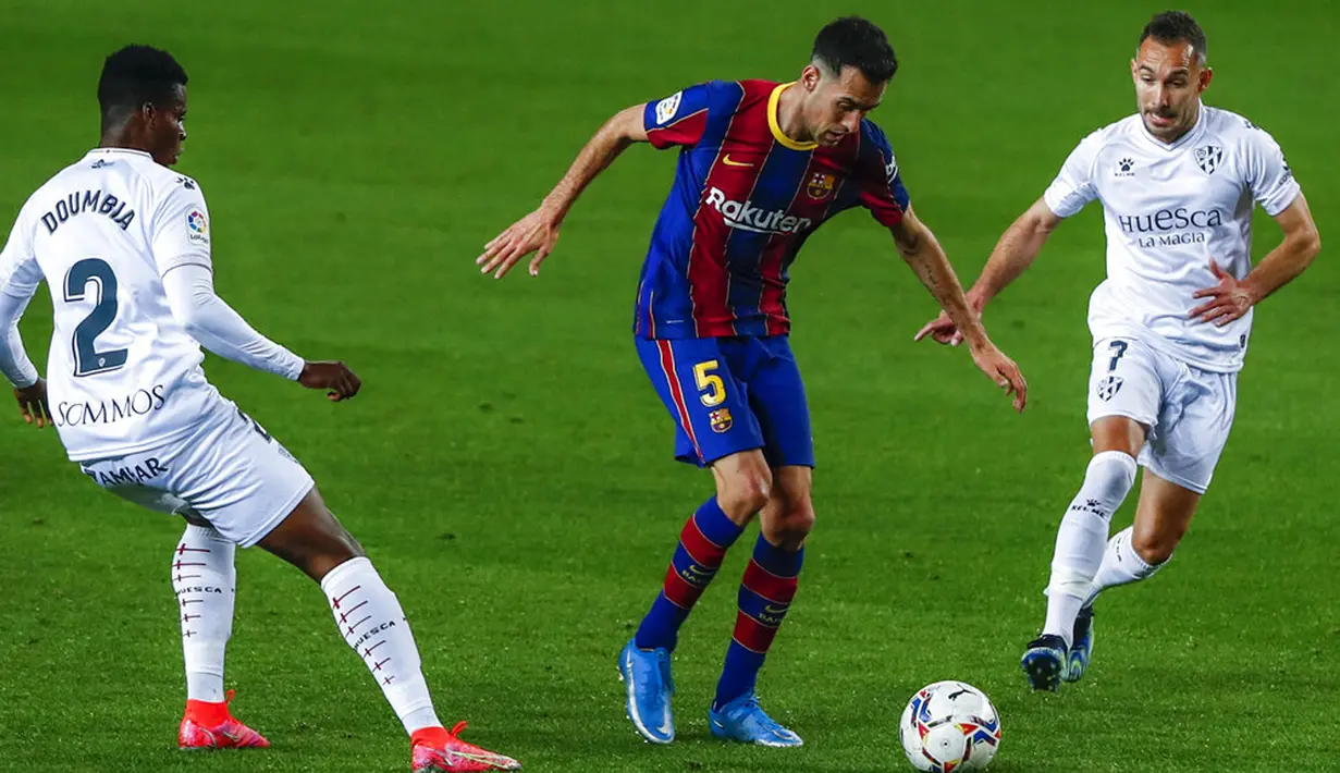 Pemain Barcelona Sergio Busquets (tengah) memperebutkan bola dengan pemain Huesca Idrissa Doumbia (kiri) dan David Ferreiro (kanan) pada pertandingan Liga Spanyol di Stadion Camp Nou, Barcelona, Spanyol, Senin (15/3/2021). Barcelona menang 4-1. (AP Photo/Joan Monfort)